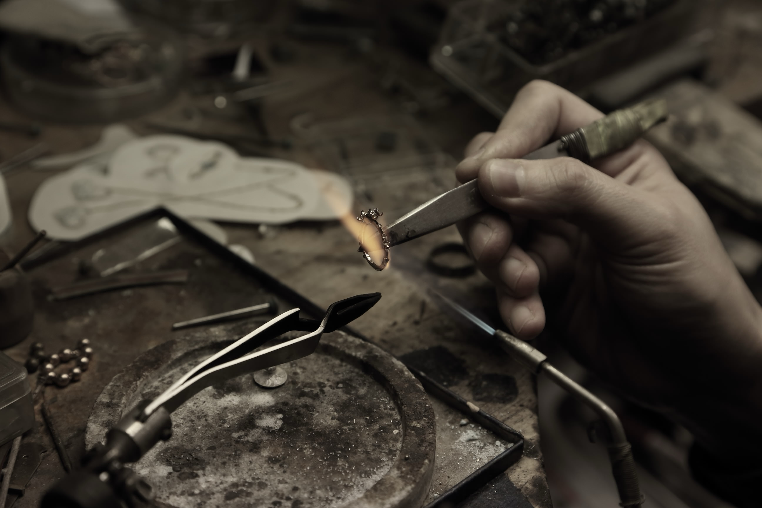 東京のkataokaアトリエで作業台に向かいロウ付けを行う金細工職人 片岡義順